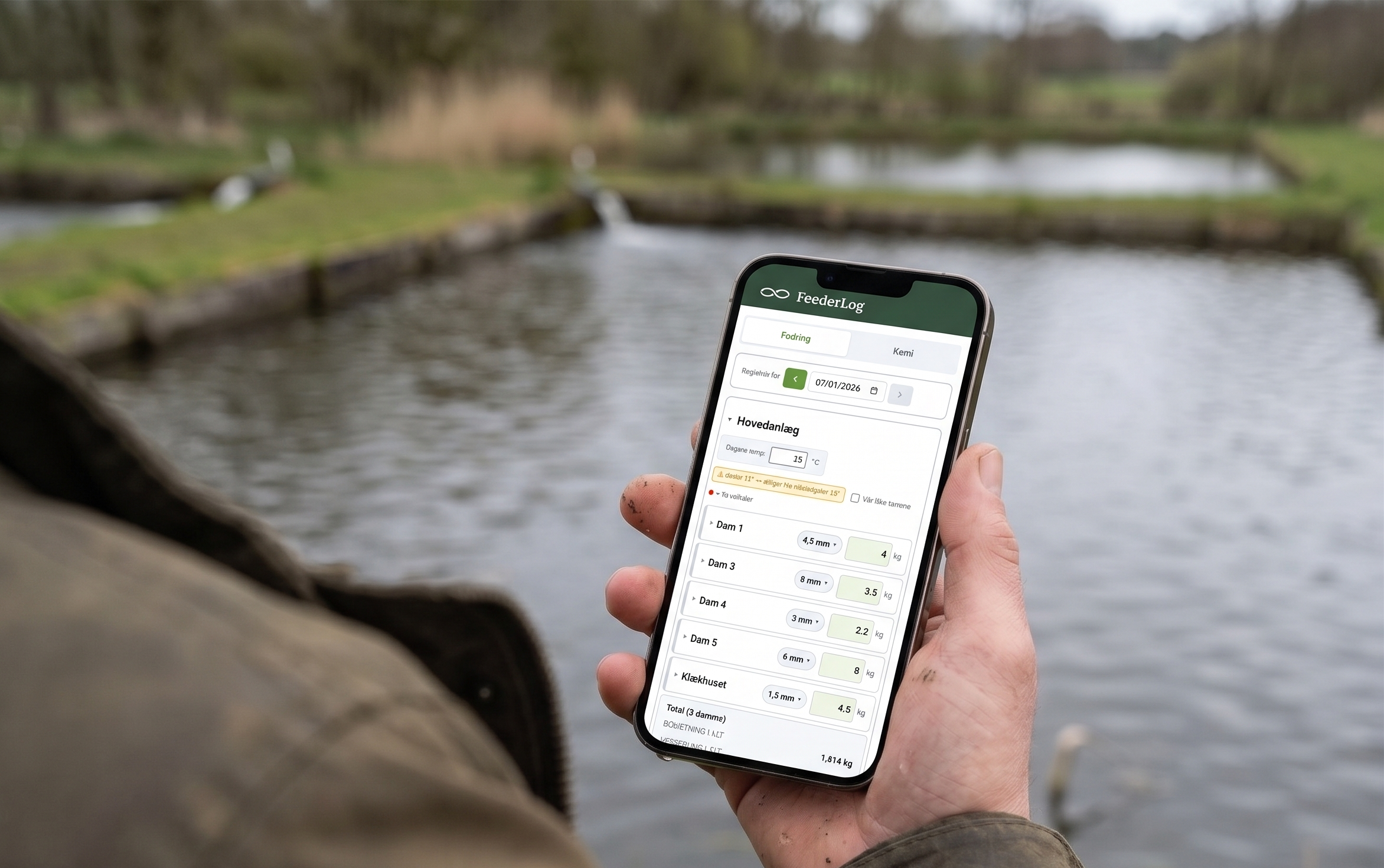 Dambruger registrerer dagens fodring på mobilen ude ved dammen - foderkort pr. dam.